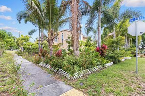 A residential area with a sidewalk, palm trees, and a house with a white fence. - 4BR Pinellas Park Beach & Game Home (Pinellas Park)