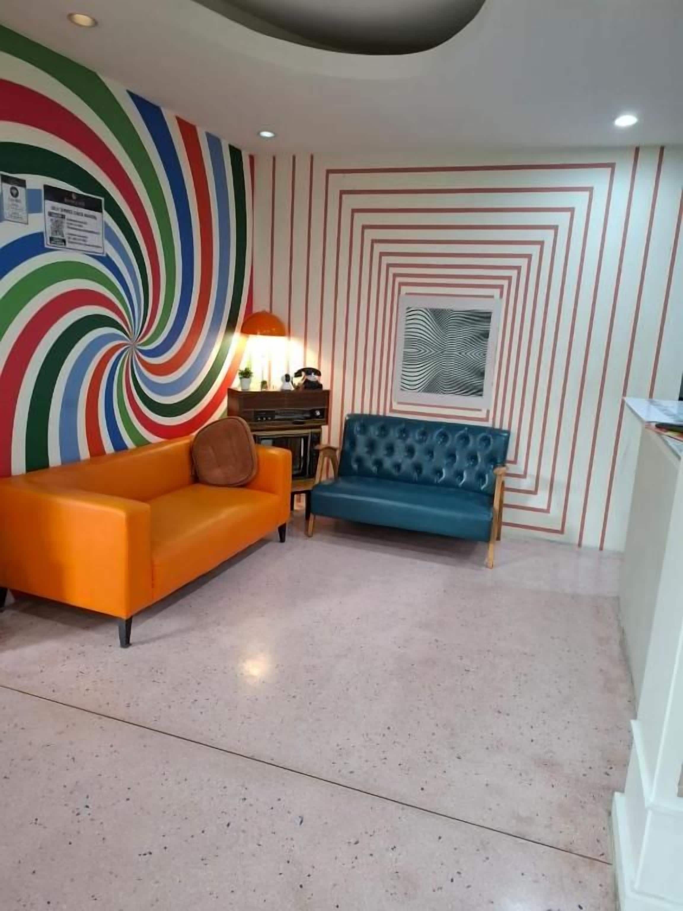 Una habitación con diseño moderno, que incluye un sofá, una silla y una pared estampada.