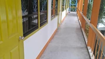 Un couloir aux portes jaunes et aux rampes orange, qui mène à une zone abritée d’où l’on peut admirer les arbres.