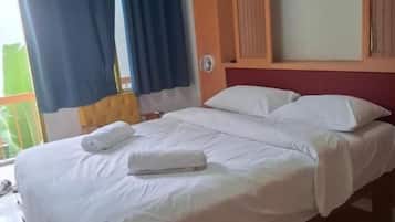 Une chambre d’hôtel avec un lit, des rideaux, une tête de lit en bois et une vue sur l’extérieur.
