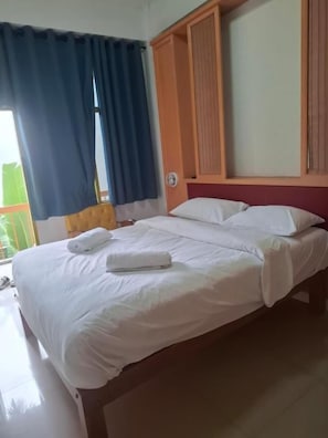 Et hotelværelse med seng, gardiner, en trægavl og udsigt ud.