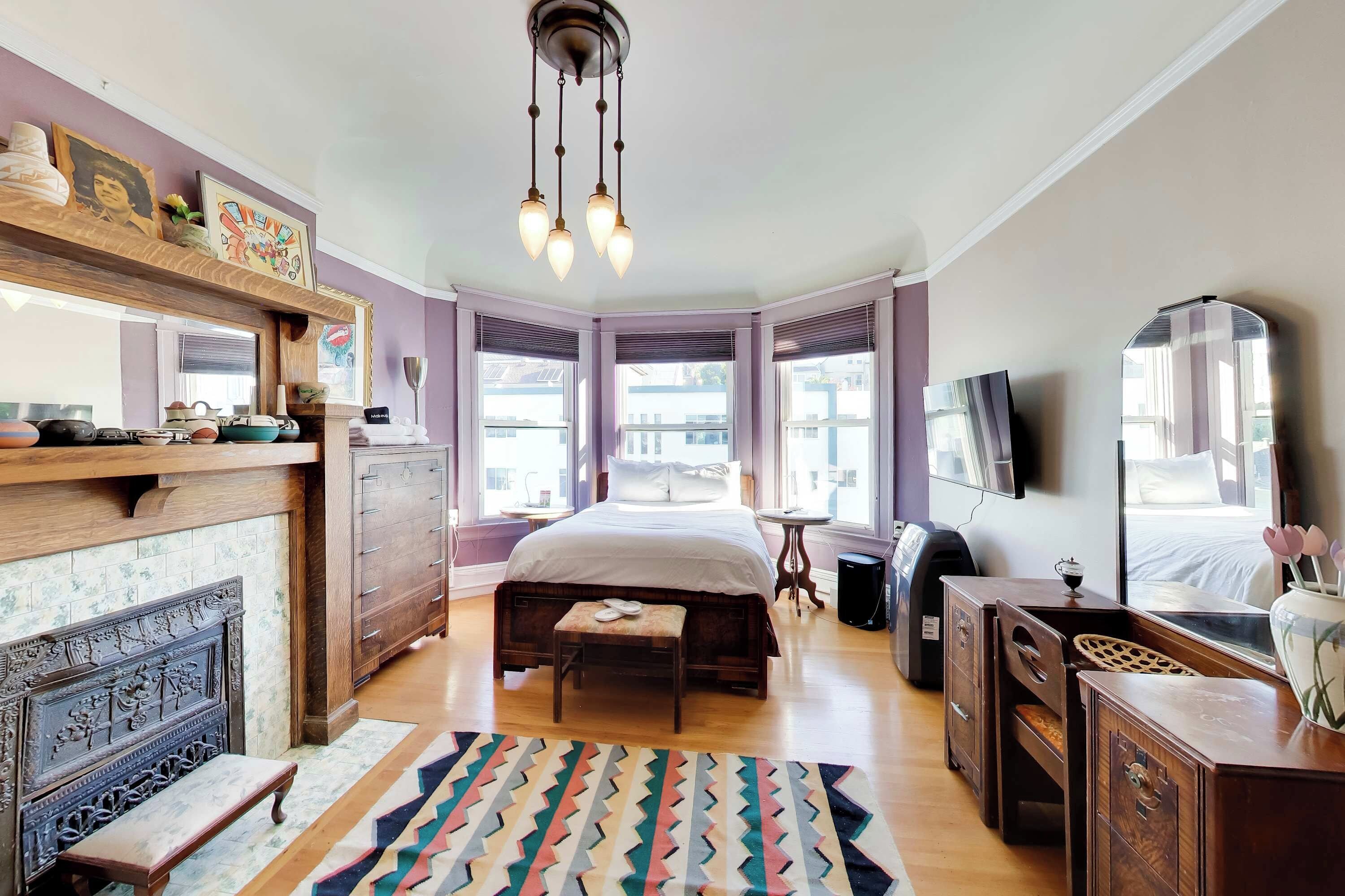 Ein Schlafzimmer mit Bett, Kommode, Spiegel und Kamin.