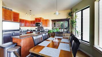A modern kitchen with wooden cabinets, stainless steel appliances, and a dining area with a large table and chairs.
