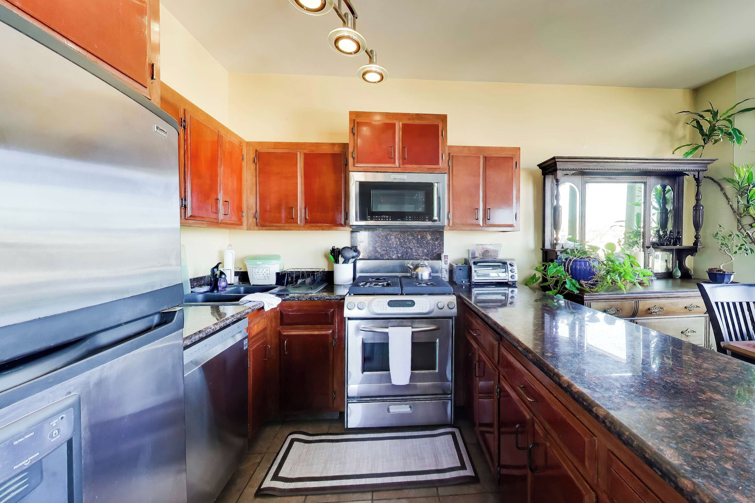 Una cocina con electrodomésticos de acero inoxidable, armarios de madera y encimera de granito.