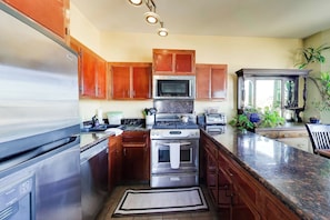 Una cocina con electrodomésticos de acero inoxidable, armarios de madera y encimera de granito.