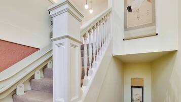 A staircase with a white balustrade, carpeted steps, and a red handrail.