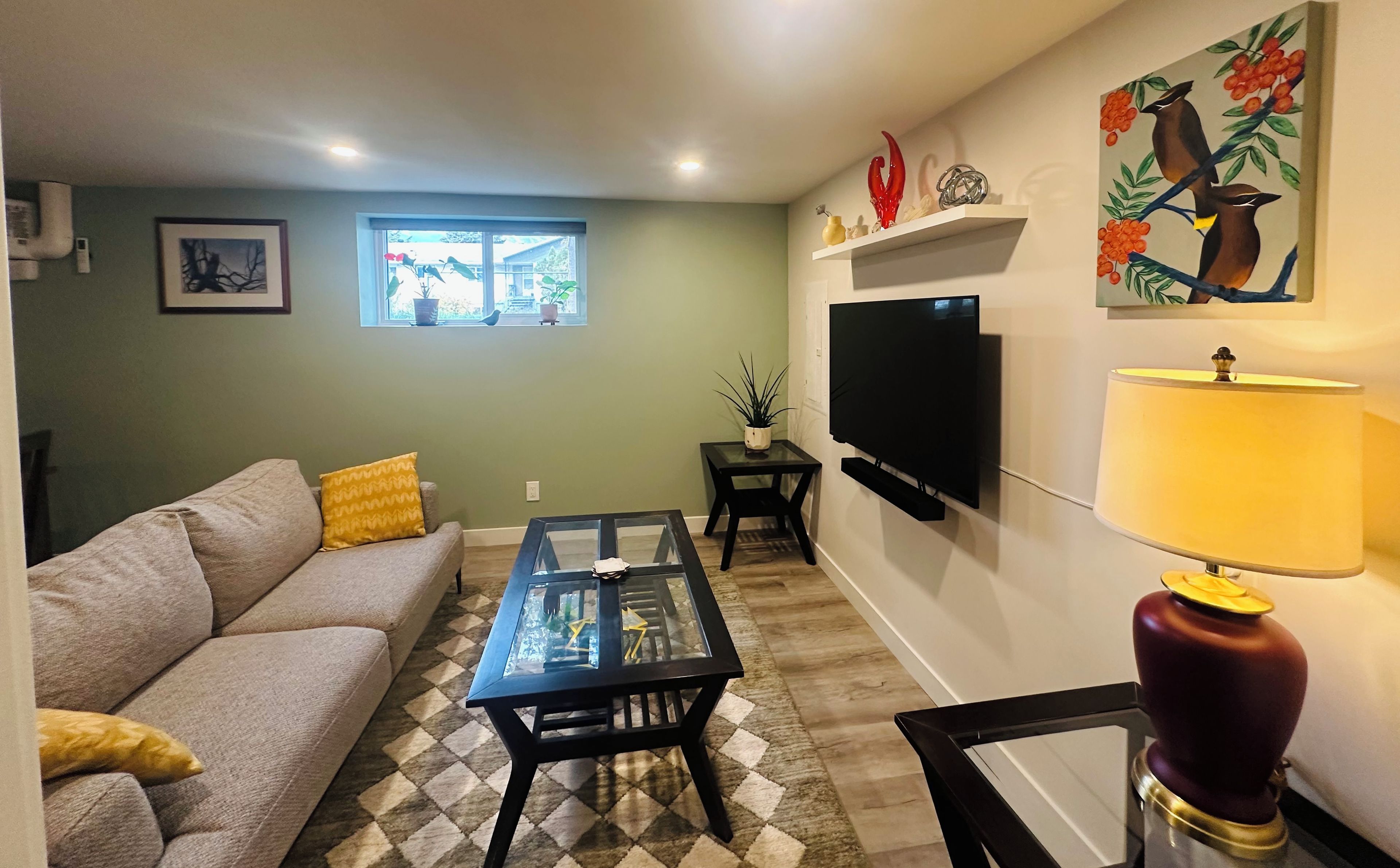 A living room with a sofa, coffee table, TV, and artwork on the wall.