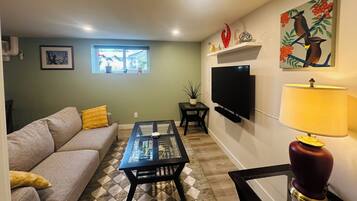 A living room with a sofa, coffee table, TV, and artwork on the wall.