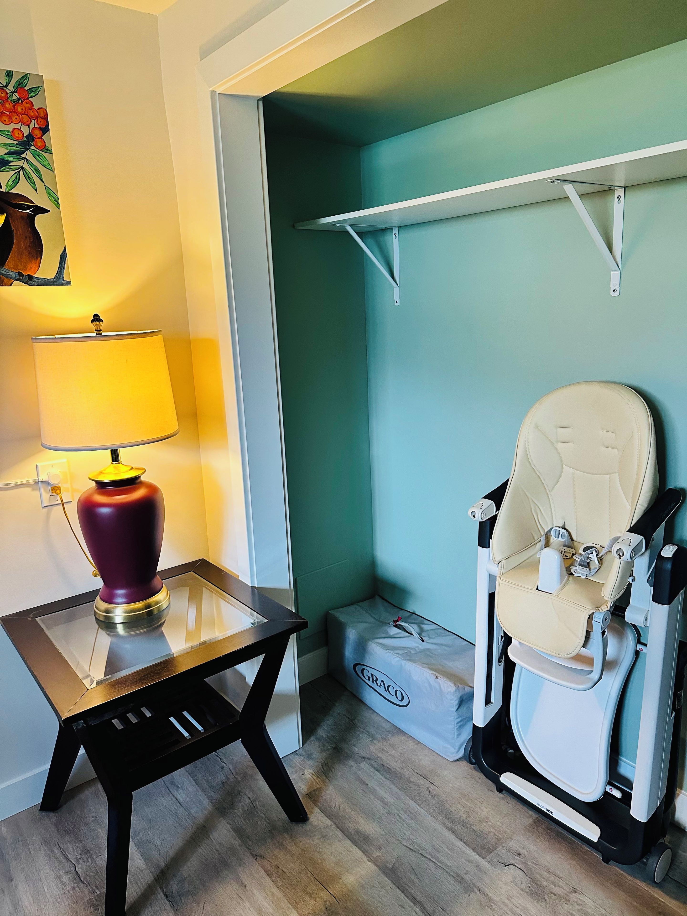 A room with a glass table, a lamp, a white toilet, and a bag labeled 'GRACO'.