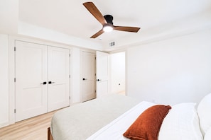 Ein Schlafzimmer mit einem Bett, einem Deckenventilator und weißen Schränken.