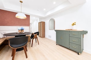 A modern dining area with a round table, two chairs, a bench, a green cabinet with drawers, a hanging pendant light, and a mirror on the wall. - Cozy 1-bedroom apartment in charming Avondale Estates BRAND NEW (Avondale Estates)
