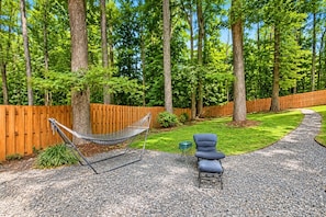 A hammock, a blue chair, and a gravel path in a wooded backyard. - Cozy 1-bedroom apartment in charming Avondale Estates BRAND NEW (Avondale Estates)