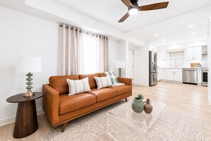 A modern living room with a leather sofa, a side table, a lamp, and a clear coffee table. - Cozy 1-bedroom apartment in charming Avondale Estates BRAND NEW (Avondale Estates)