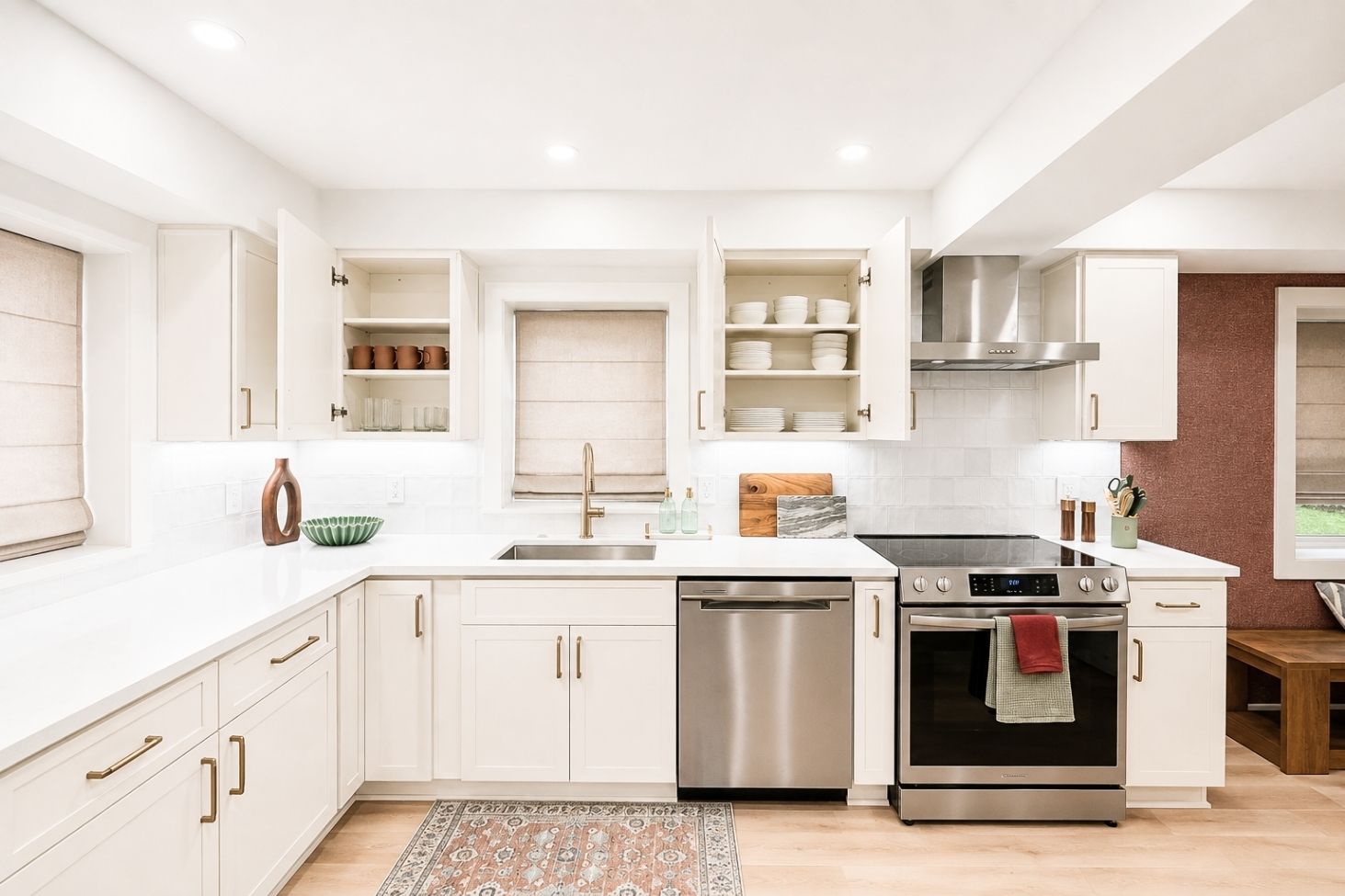 Une cuisine moderne avec des meubles blancs, des appareils en acier inoxydable et un tapis à motifs.