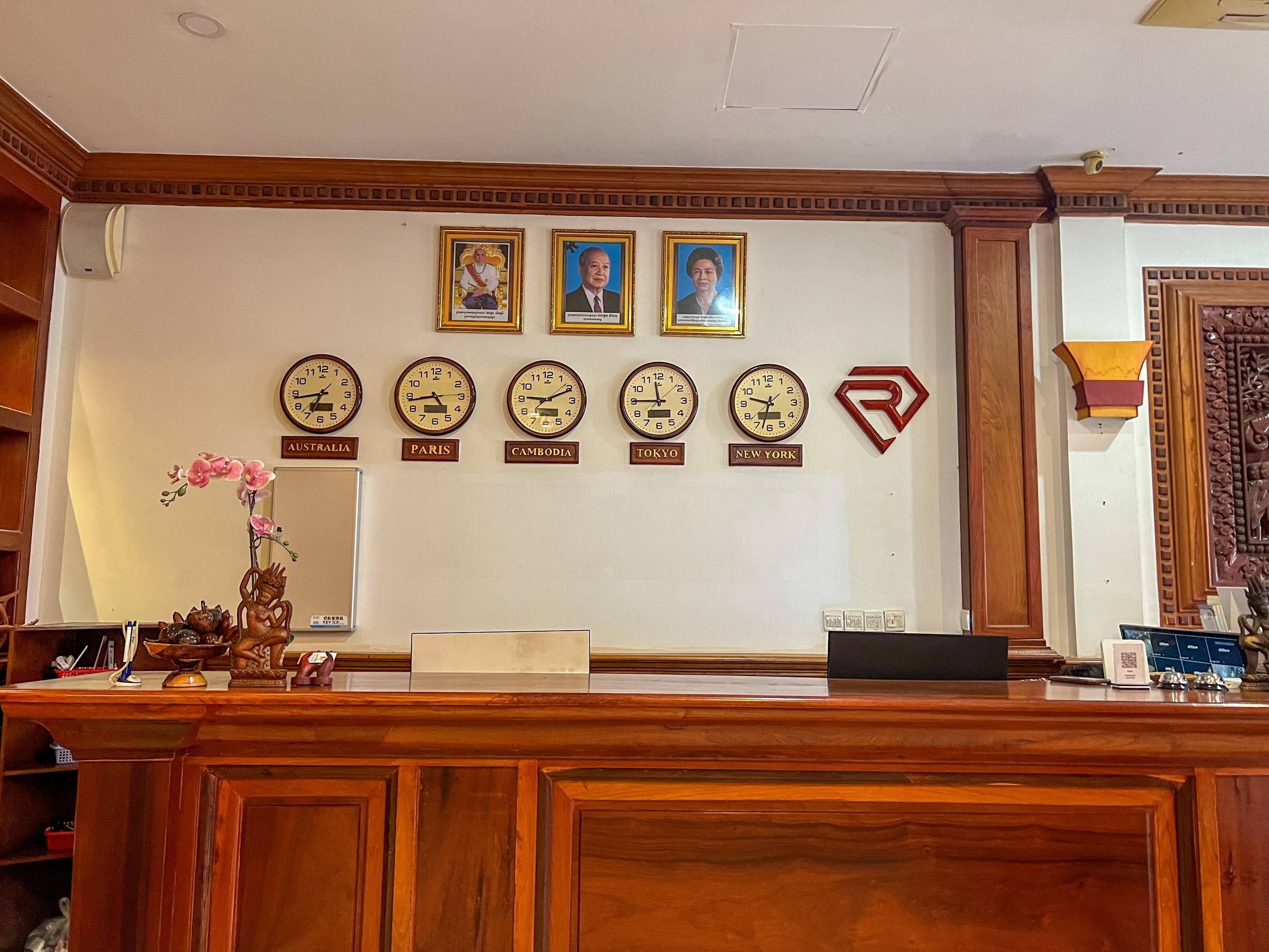 Una recepción con relojes mostrando diferentes ciudades, un arreglo floral y un emblema decorativo.