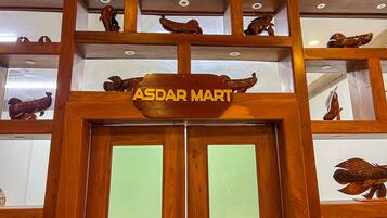 Un letrero de madera que dice 'ASDAR MART', indicando una tienda o servicio dentro de un edificio de estilo arquitectónico tradicional.