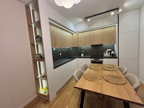 A modern kitchen with built-in cabinets, a black countertop, and a wooden dining table with placemats.