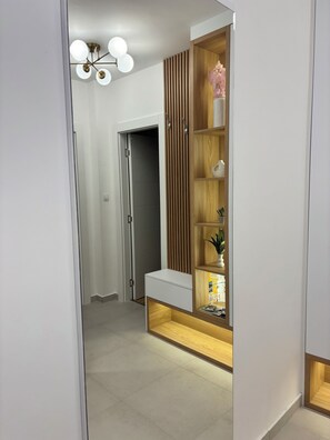 Ein moderner Flur mit einer eingebauten Holzhängeschiene, einer weißen Bank und einer Deckenleuchte.