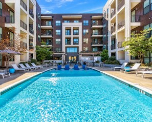 A modern apartment building with a central swimming pool, lounge chairs, and outdoor seating. - 5 Minutes to Downtown + Pool + Fitness Gym + Free Parking (Nashville)