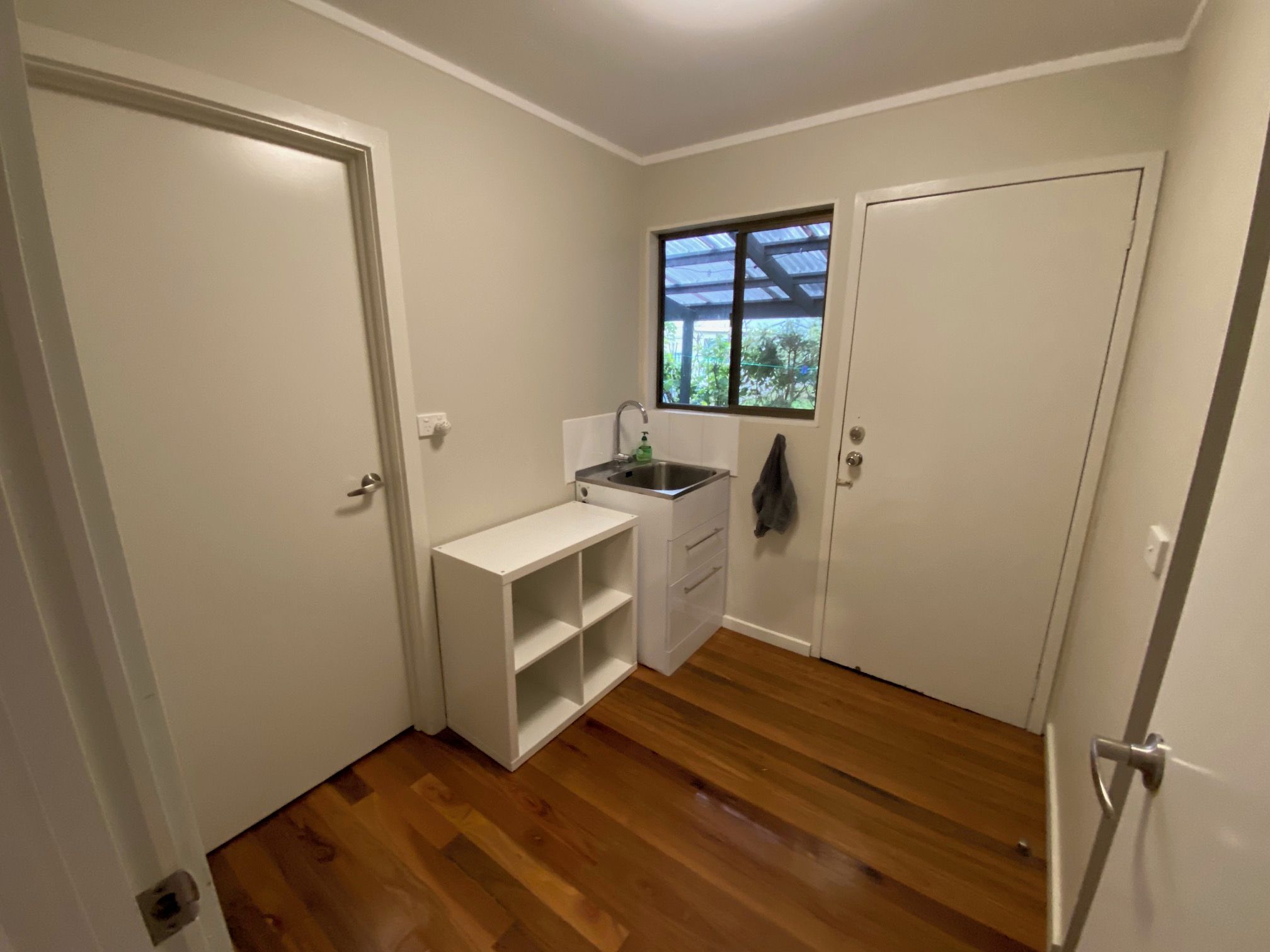 A compact kitchen with a sink, a window, and a door.