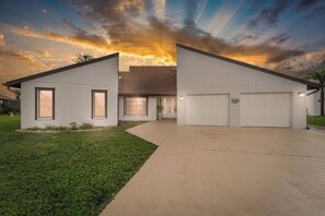 Une maison moderne à deux étages, dotée d’un garage, d’une pelouse bien entretenue et d’une allée menant à l’entrée.
