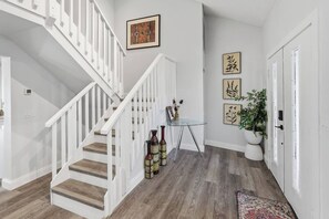 A staircase with white railings, a glass table with a vase, and framed artwork on the walls. - Canalfront Pool Home near Port Charlotte • Gulf Access & Fishing Ramp (Port Charlotte)