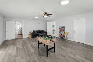 A room with a foosball table, a ceiling fan, and a sofa. - Canalfront Pool Home near Port Charlotte • Gulf Access & Fishing Ramp (Port Charlotte)
