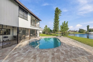 A two-story house with a swimming pool, a covered patio, and a view of a lake. - Canalfront Pool Home near Port Charlotte • Gulf Access & Fishing Ramp (Port Charlotte)