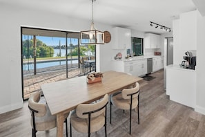 Une cuisine moderne avec une grande table à manger, des meubles blancs et une vue sur une piscine.