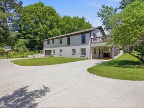 Ein zweistöckiges Wohnhaus mit überdachter Veranda und Auffahrt.