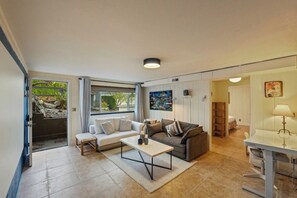 A modern living room with a sofa, a coffee table, and a dining area with a lamp. - Queen Anne Home, Space Needle Walk + Parking (Seattle)