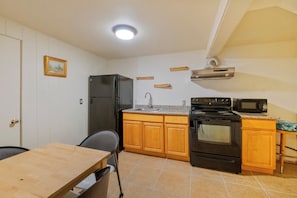 A compact kitchen with a refrigerator, stove, microwave, and wooden cabinets. - Queen Anne Home, Space Needle Walk + Parking (Seattle)