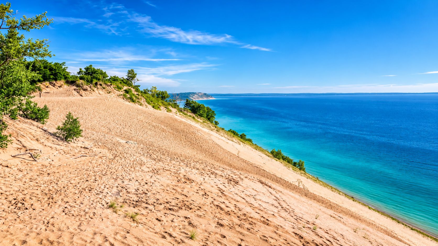 Ein sandiger Strand mit klarem, blauem Wasser und einer fernen Küstenlinie.