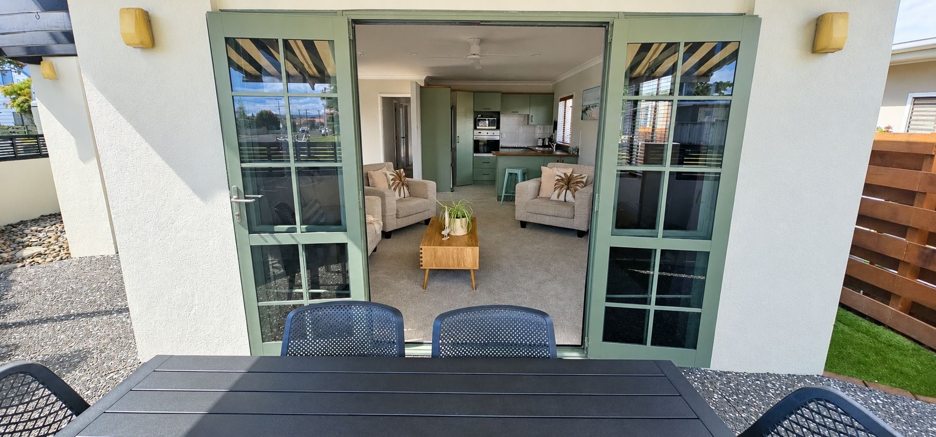An open patio with a table and chairs, a sofa, and a kitchen in the background.