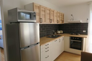 A modern kitchen with a refrigerator, microwave, and oven. - St Cath's Anchorage 2 Bedroom (Wynnum)
