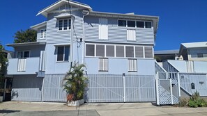 A two-story residential building with a garage, a covered patio, and a gated driveway. - St Cath's Anchorage 2 Bedroom (Wynnum)