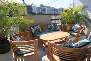 An outdoor seating area with wooden furniture and patterned cushions. - St Cath's Anchorage 2 Bedroom (Wynnum)