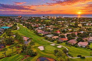 A golf course with a sunset view, surrounded by residential buildings and a body of water. - Burnt Store Marina 2 Bedroom Condo (Punta Gorda)