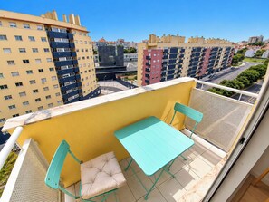 Ein Balkon mit Tisch und Stühlen, mit Blick auf ein Wohngebiet mit Mehrfamilienhäusern.
