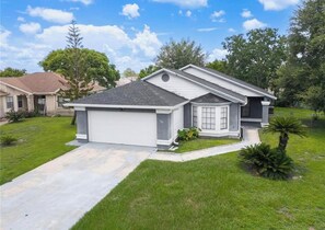 A single-story house with a garage, a front porch, and a well-maintained lawn. - Modern Kissimmee Retreat Near Disney & Universal (Kissimmee)