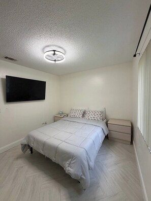 Ein Schlafzimmer mit einem Bett, Nachttischen, einem Fernseher und einem Deckenventilator.