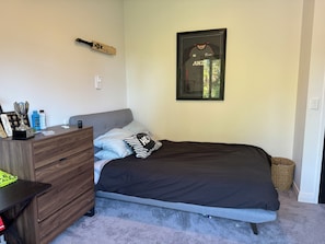 A bedroom with a bed, a dresser, a framed jersey, and a trophy on the dresser. - Country resort -  Have fun with your extended family at this stylish home (Whakamārama)