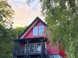 Punainen rakennus, jossa on parveke, ja sen ympärillä on puita.