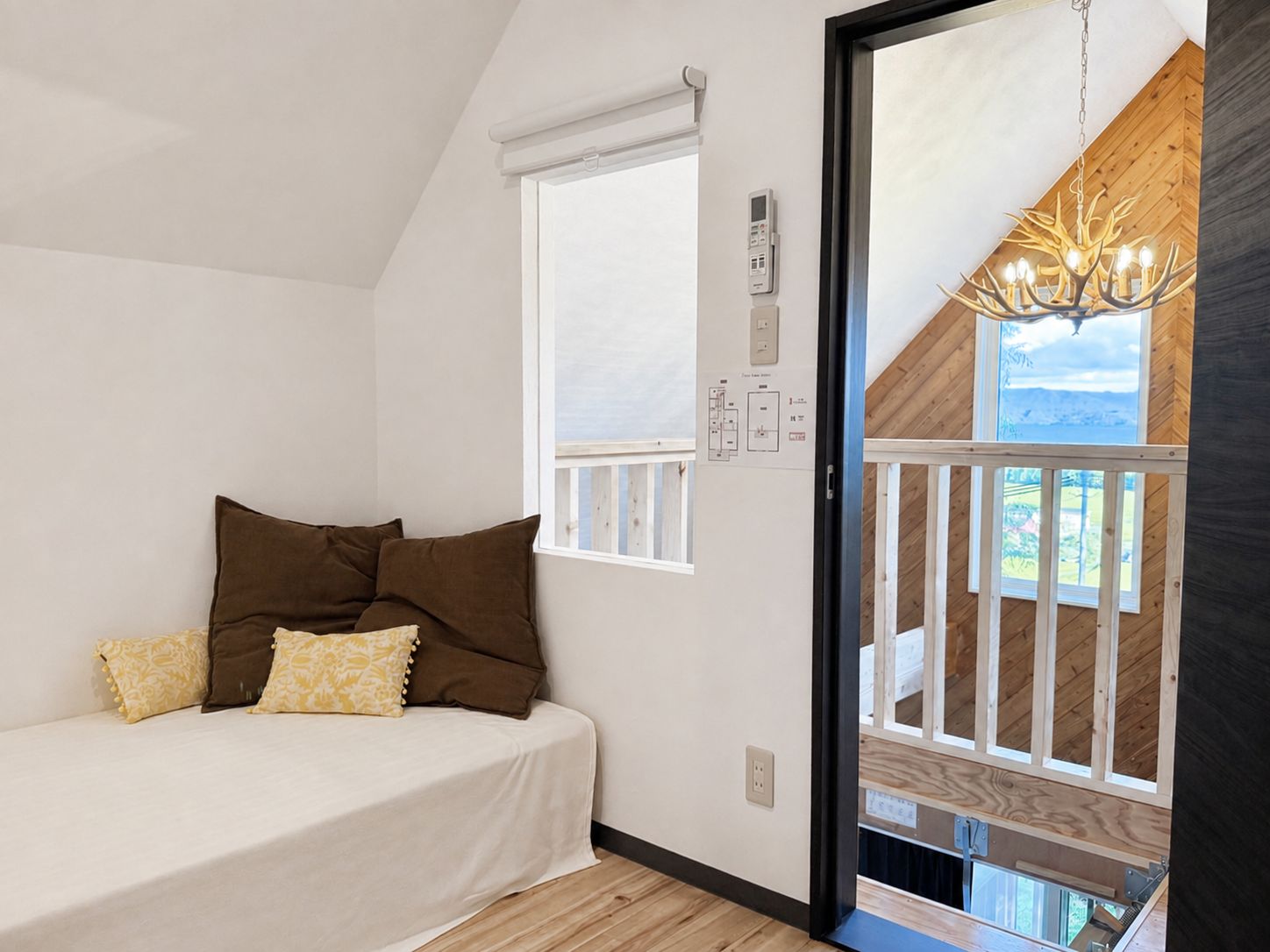 Une chambre à coucher avec un lit, des oreillers, une fenêtre, un panneau de commande fixé au mur et une vue sur l’extérieur.