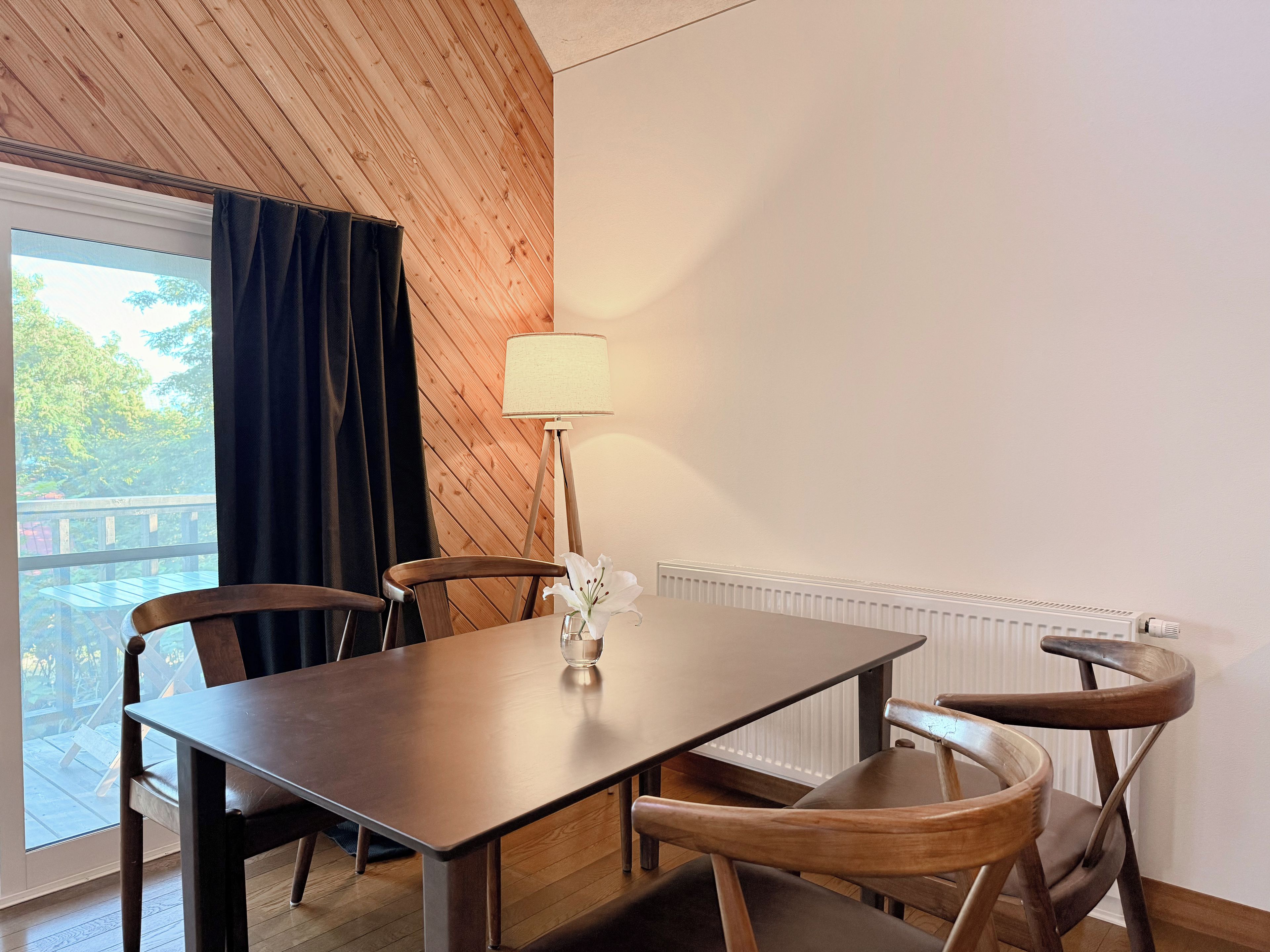 Un comedor con una mesa, sillas, una lámpara y vistas al exterior.
