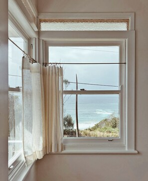 A window with a view of the ocean, a curtain, and a power line. - Restored Vintage Seaside Home with Pacific Ocean Views (Port Macquarie)