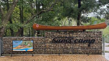 A stone wall with a canoe and a sign for 'Sam's Camp' with a map and contact information.