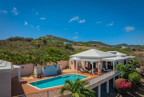 A poolside area with a covered seating area, a pool, and a view of a hilly landscape. - Welcome to Villa Amarante , Your East End Caribbean Escape! (Christiansted)
