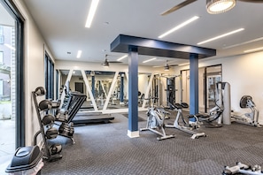 A gym with exercise equipment, mirrors, and a view of the outside. - Mid-century | 5 minutes to Downtown & Broadway |Fitness Gym + Free Parking (Nashville)