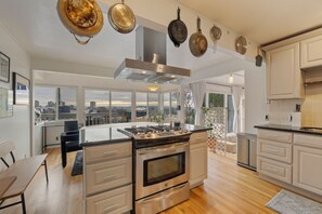 A modern kitchen with a central island, stainless steel appliances, and a city view through large windows. - 2BR Queen Anne Home - Space Needle View + Deck (Seattle)